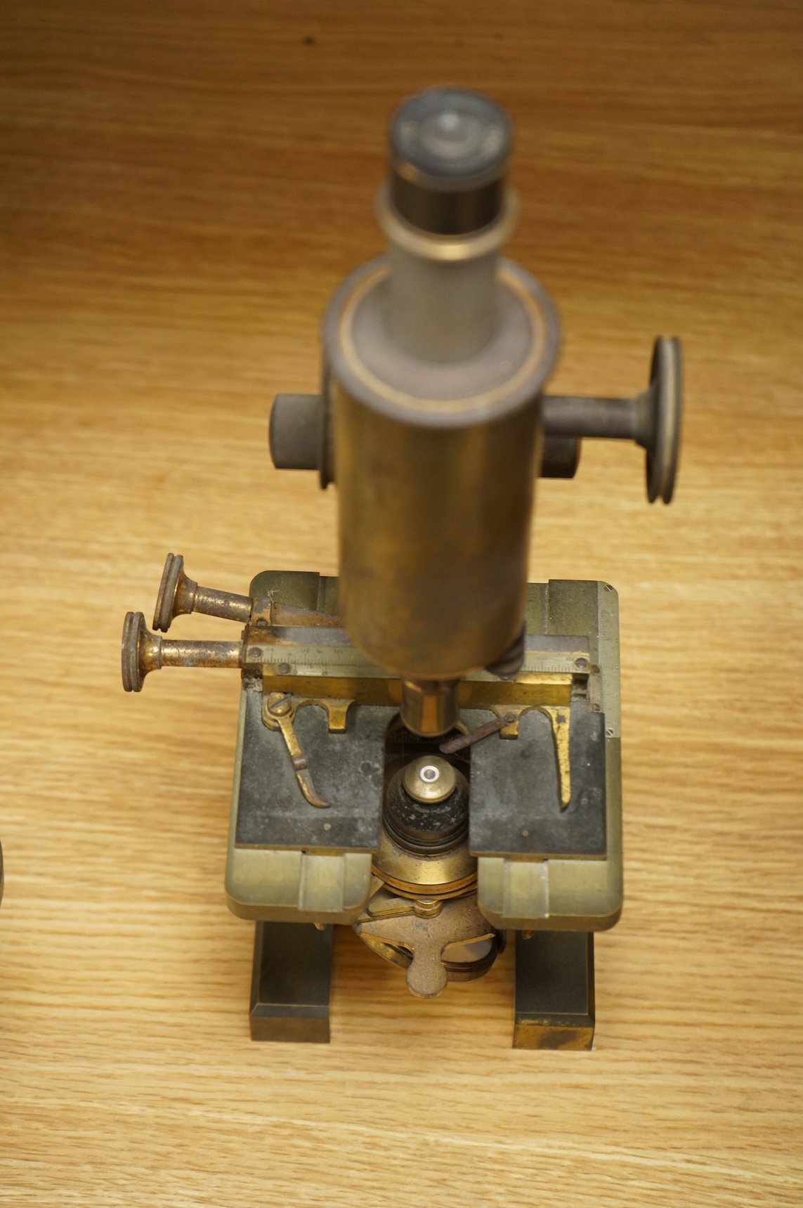 An early 20th century brass compound monocular microscope, by R & J Beck, Ltd., London, number 33007, with accessories including spare lenses, a free standing magnifier and objectives, mahogany cased; 34.5cm high, 19cm w